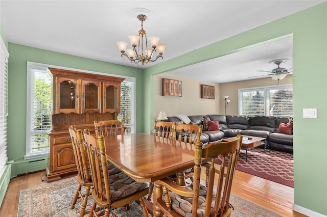 dining space with ceiling fan with notable chandelier and light wood-style floors