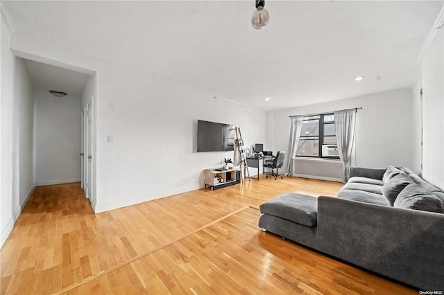 living room featuring light wood-type flooring, ornamental molding, and baseboards