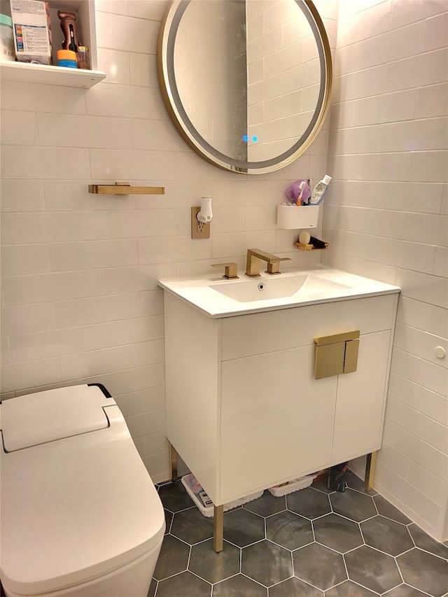 half bathroom featuring tile walls, toilet, tile patterned flooring, and vanity