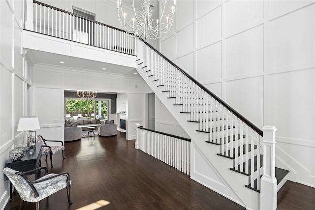 471 Middle Line Hwy, Sag Harbor, NY 11963 - staircase with a chandelier, a decorative wall, wood finished floors, and a high ceiling