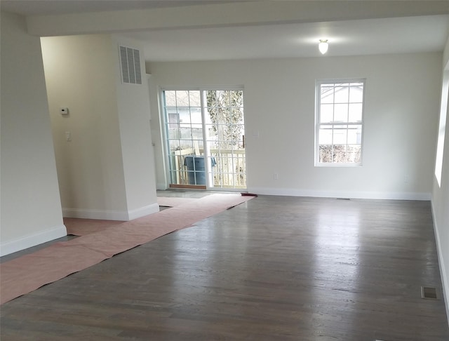 spare room with wood finished floors, visible vents, a healthy amount of sunlight, and baseboards