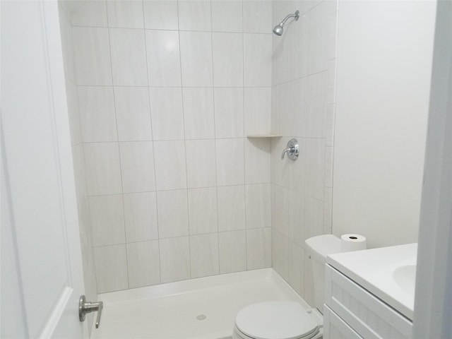 bathroom featuring toilet, a tile shower, and vanity