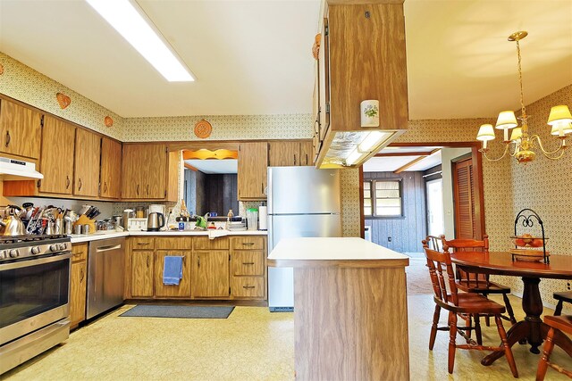 kitchen featuring wallpapered walls, under cabinet range hood, appliances with stainless steel finishes, light countertops, and brown cabinets