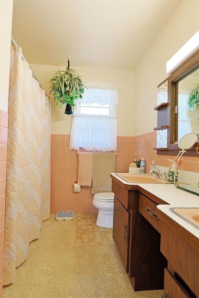 full bathroom featuring curtained shower, double vanity, toilet, tile walls, and wainscoting