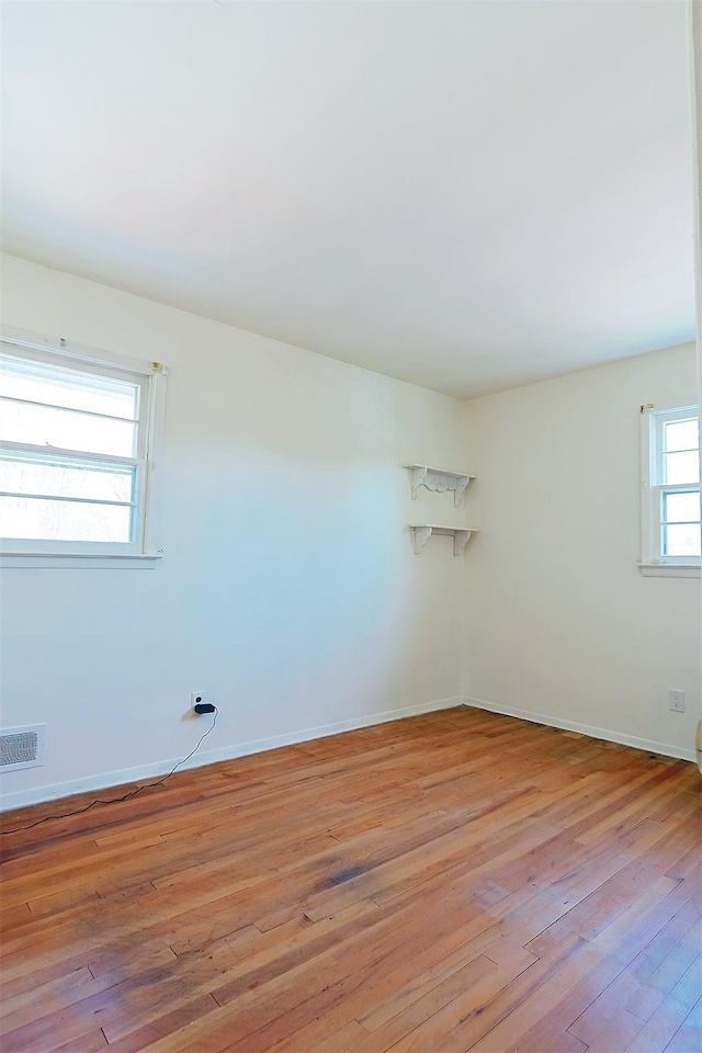 empty room with visible vents, light wood-style flooring, and baseboards