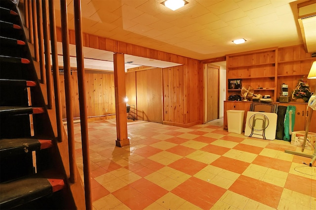 finished basement with wood walls, light floors, and stairway