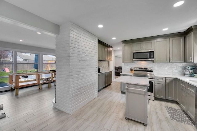 kitchen featuring a center island, gray cabinetry, appliances with stainless steel finishes, and tasteful backsplash