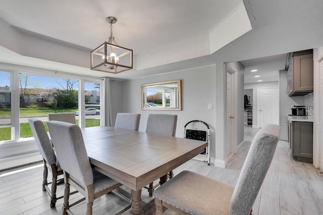 dining area featuring recessed lighting, an inviting chandelier, light wood-style floors, baseboards, and a tray ceiling