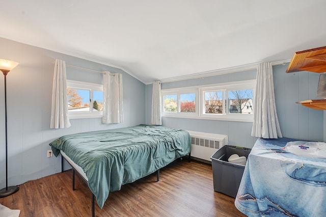 bedroom featuring radiator heating unit, vaulted ceiling, and wood finished floors