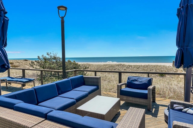 wooden terrace with a water view, outdoor lounge area, and a view of the beach
