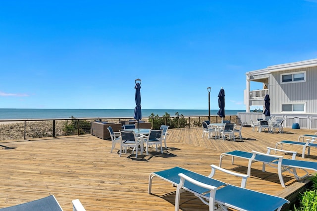 wooden terrace featuring outdoor dining space and a water view