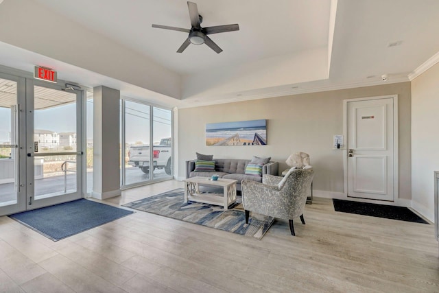 living area featuring a healthy amount of sunlight, ceiling fan, ornamental molding, and wood finished floors