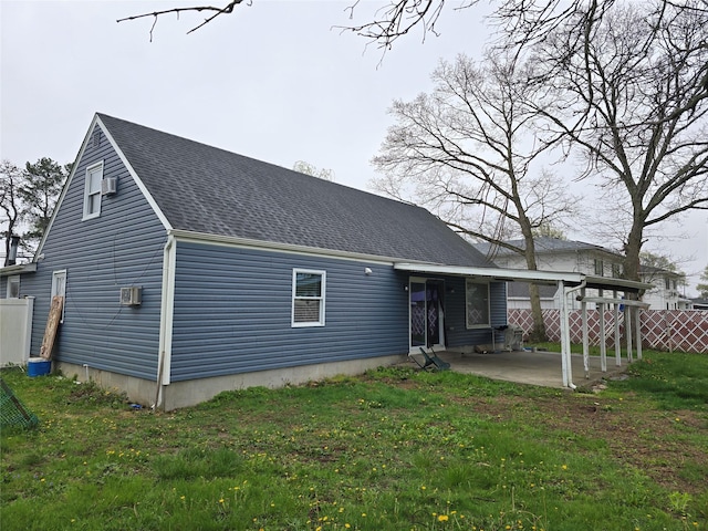 rear view of house with a patio, roof with shingles, fence, and a lawn