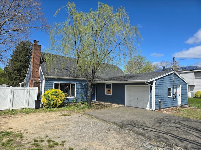 view of front of home with driveway, a chimney, fence, an attached garage, and a shingled roof