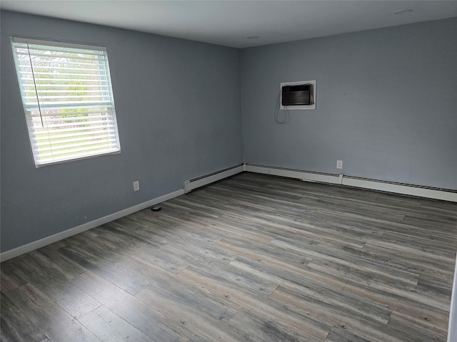 empty room with an AC wall unit, a baseboard radiator, wood finished floors, and baseboards
