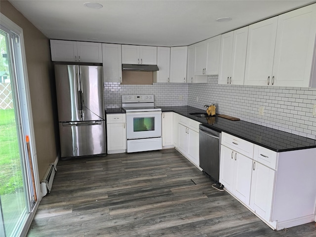kitchen featuring dark countertops, a baseboard heating unit, under cabinet range hood, a sink, and stainless steel appliances