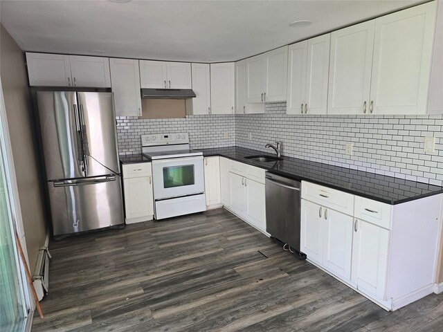 kitchen featuring a sink, under cabinet range hood, dark countertops, and stainless steel appliances