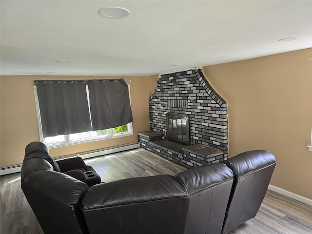 living room with baseboards, a baseboard radiator, a brick fireplace, and wood finished floors