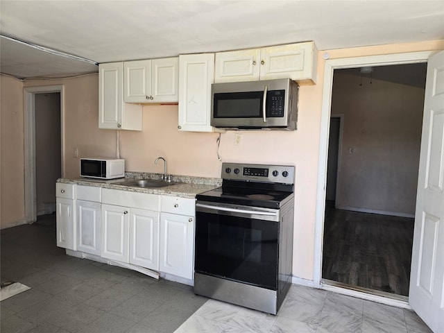 kitchen featuring a sink, appliances with stainless steel finishes, white cabinets, and light countertops