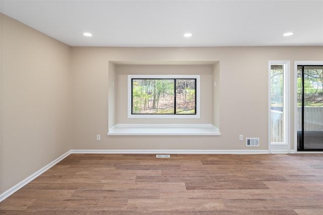 empty room featuring baseboards, wood finished floors, and visible vents