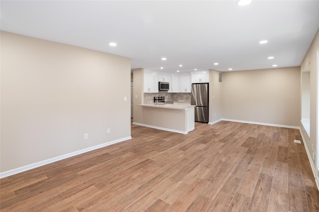 unfurnished living room featuring light wood-style floors, baseboards, and recessed lighting