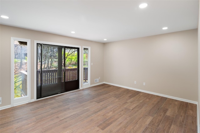unfurnished room with recessed lighting, baseboards, wood finished floors, and visible vents