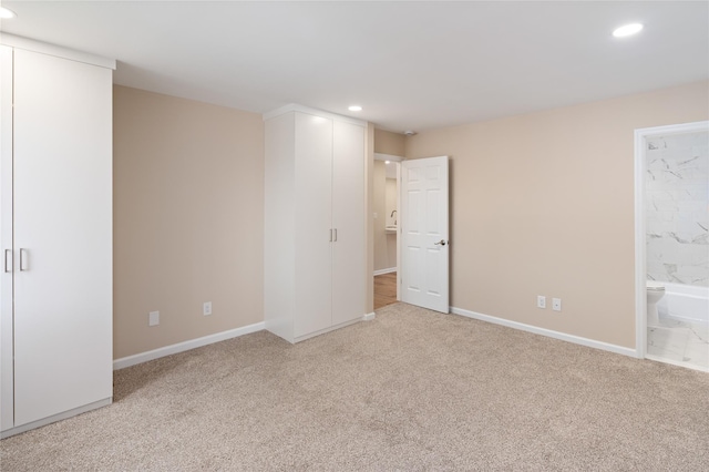 unfurnished bedroom with recessed lighting, baseboards, ensuite bathroom, and carpet