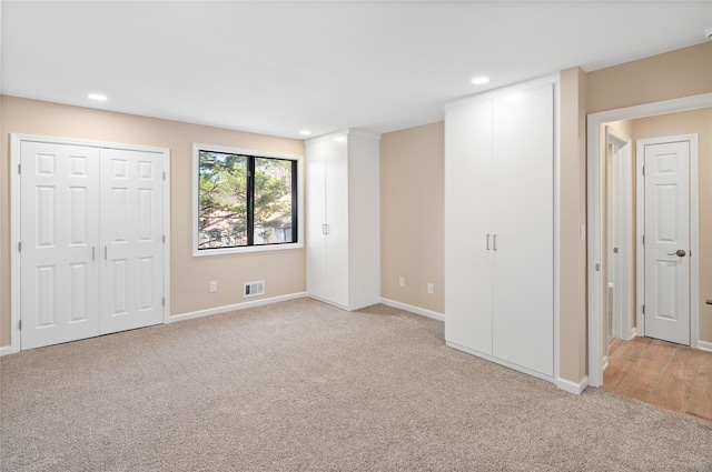 unfurnished bedroom featuring baseboards, light colored carpet, recessed lighting, and visible vents