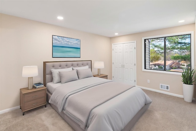 bedroom with baseboards, visible vents, light carpet, and a closet