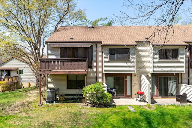 back of property with central AC unit, a patio area, a yard, and a shingled roof