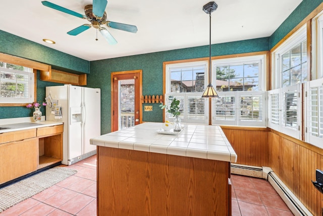 kitchen with plenty of natural light, light tile patterned flooring, white refrigerator with ice dispenser, and a baseboard radiator