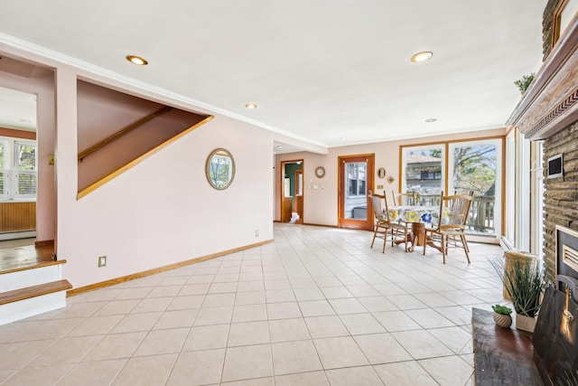 unfurnished living room featuring baseboards, recessed lighting, a baseboard heating unit, and a stone fireplace