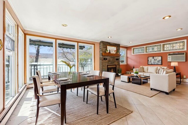 dining area featuring light tile patterned floors, a baseboard radiator, a large fireplace, ornamental molding, and a wall mounted air conditioner