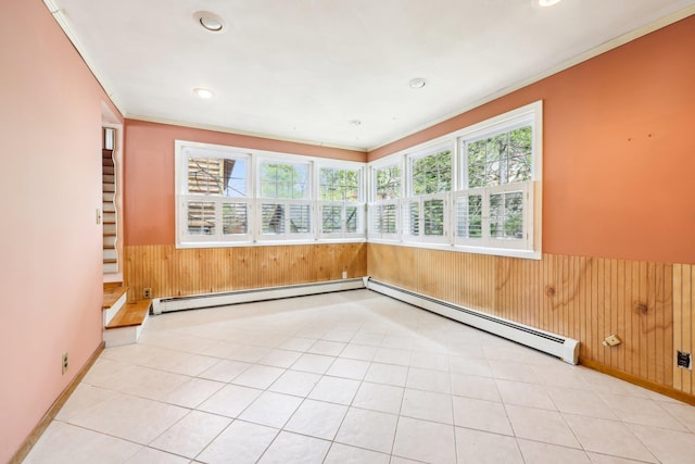 unfurnished room featuring ornamental molding, wainscoting, wood walls, and a baseboard radiator