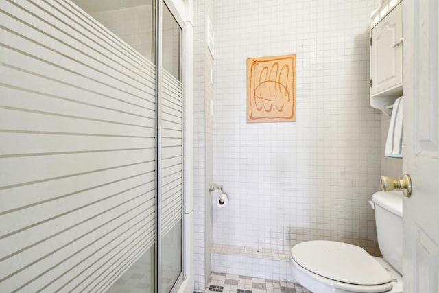 full bathroom with toilet, a stall shower, and tile walls