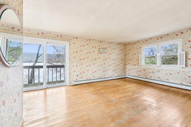 spare room with a baseboard radiator, light wood-style flooring, and wallpapered walls