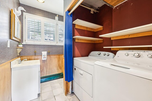 clothes washing area featuring light tile patterned floors, washer and clothes dryer, laundry area, and a sink