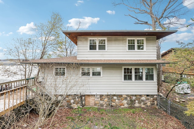 rear view of house featuring fence, roof with shingles, and a wooden deck