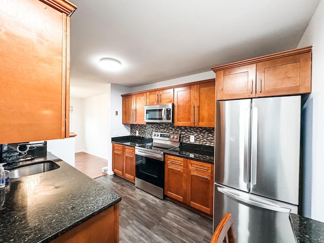 kitchen with backsplash, appliances with stainless steel finishes, brown cabinets, dark wood finished floors, and a sink