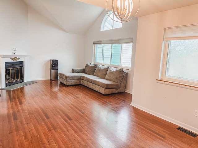 living area with a notable chandelier, visible vents, wood finished floors, and lofted ceiling