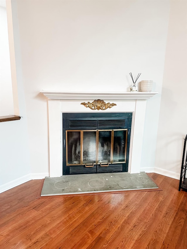 interior details featuring baseboards, a glass covered fireplace, and wood finished floors