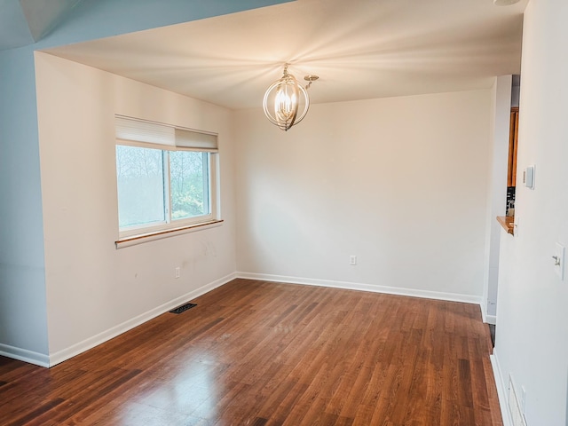 spare room with baseboards, visible vents, dark wood-style floors, and an inviting chandelier