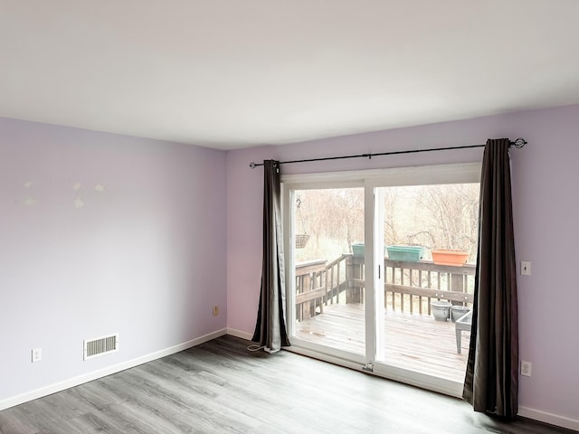 unfurnished room with baseboards, visible vents, and wood finished floors