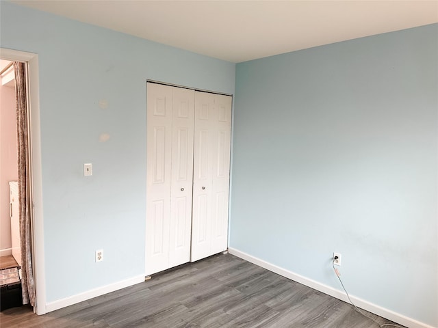 unfurnished bedroom with baseboards, wood finished floors, and a closet