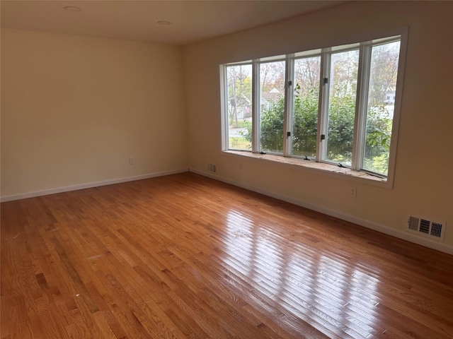 empty room featuring visible vents, baseboards, and wood finished floors