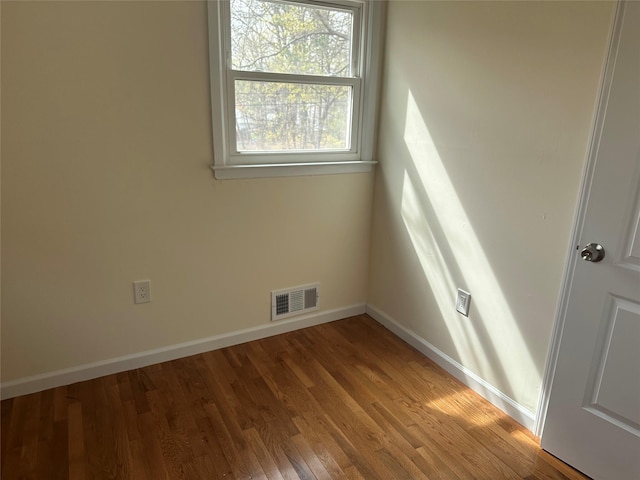 spare room featuring visible vents, baseboards, and wood finished floors
