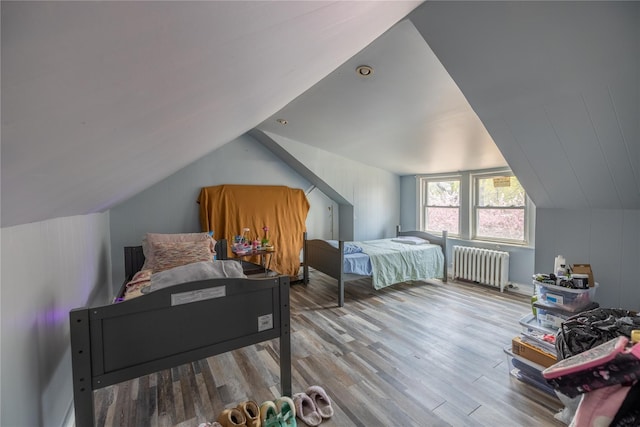 bedroom featuring lofted ceiling, wood finished floors, and radiator