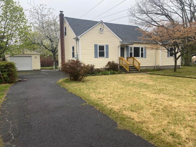 view of front of house featuring roof with shingles, aphalt driveway, a front yard, an outbuilding, and a chimney