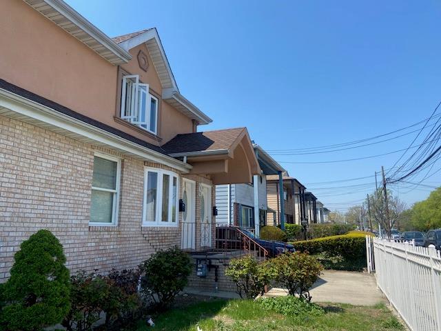 view of side of property with fence, stucco siding, and brick siding