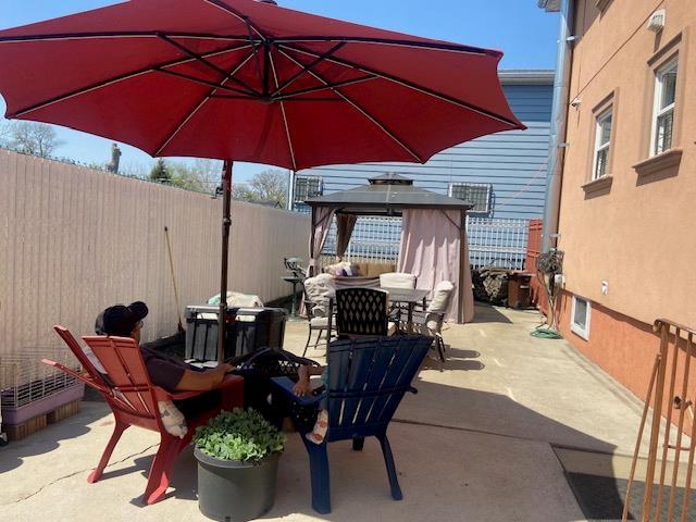 view of patio with fence, outdoor dining space, and a gazebo